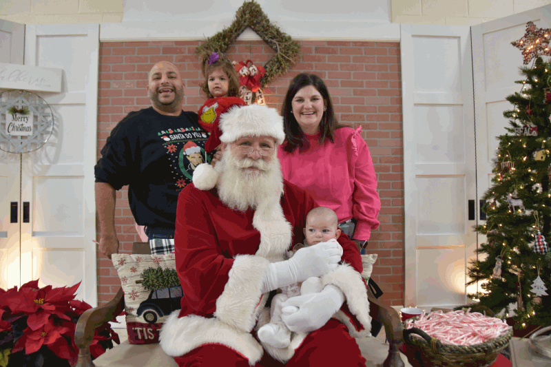 Family posing with Santa who is holding baby.